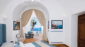 A bedroom with a large bed, a view of the sea through an arched window, and a door leading to a balcony. - The Most Panoramic Villa In The Center Of Positano (Positano)