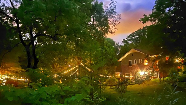 Una casa rodeada de árboles con luces colgantes.