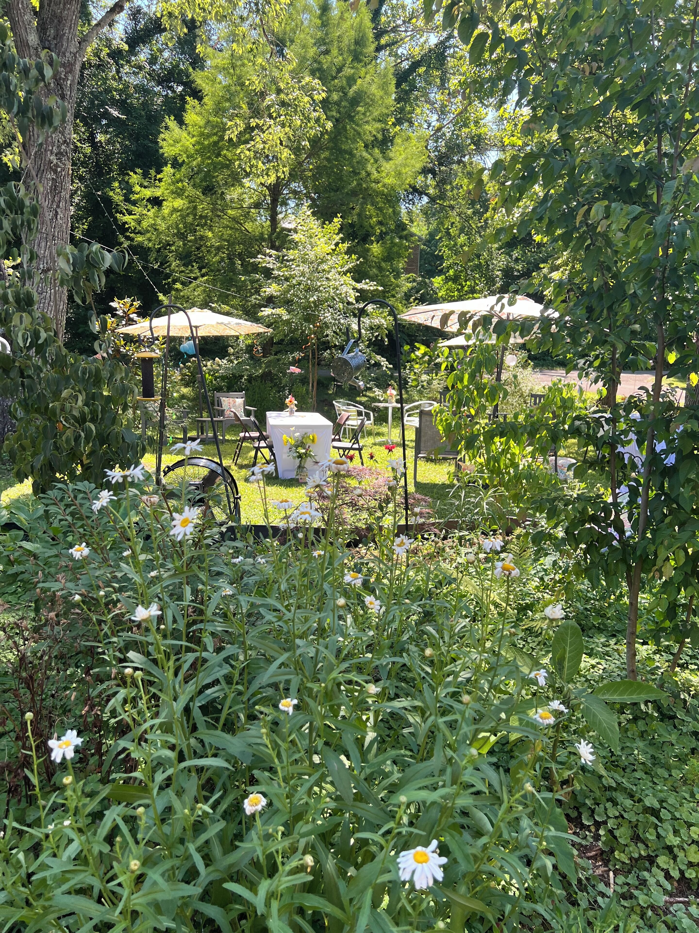 A garden area with a gazebo, outdoor seating, and a variety of plants and flowers.