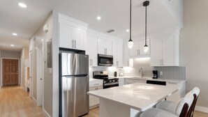 Una cocina moderna con armarios blancos, electrodomésticos de acero inoxidable y una isla central.
