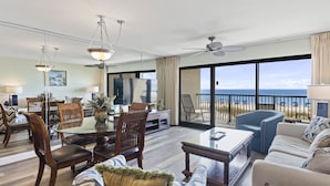 A spacious living area with a large glass door leading to a balcony with a view of the ocean. There is a dining table with chairs, a sofa, and a coffee table. - 202- Offers AMAZING GULF VIEWS from private balcony. Destin Beach Club (Destin)