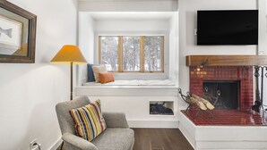 En hyggelig stue med pejs, en vindueskarm, et fjernsyn og en lampe.