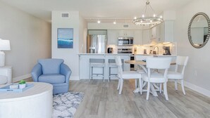 A modern kitchen with white cabinets, a dining area with white chairs, and a chandelier.
