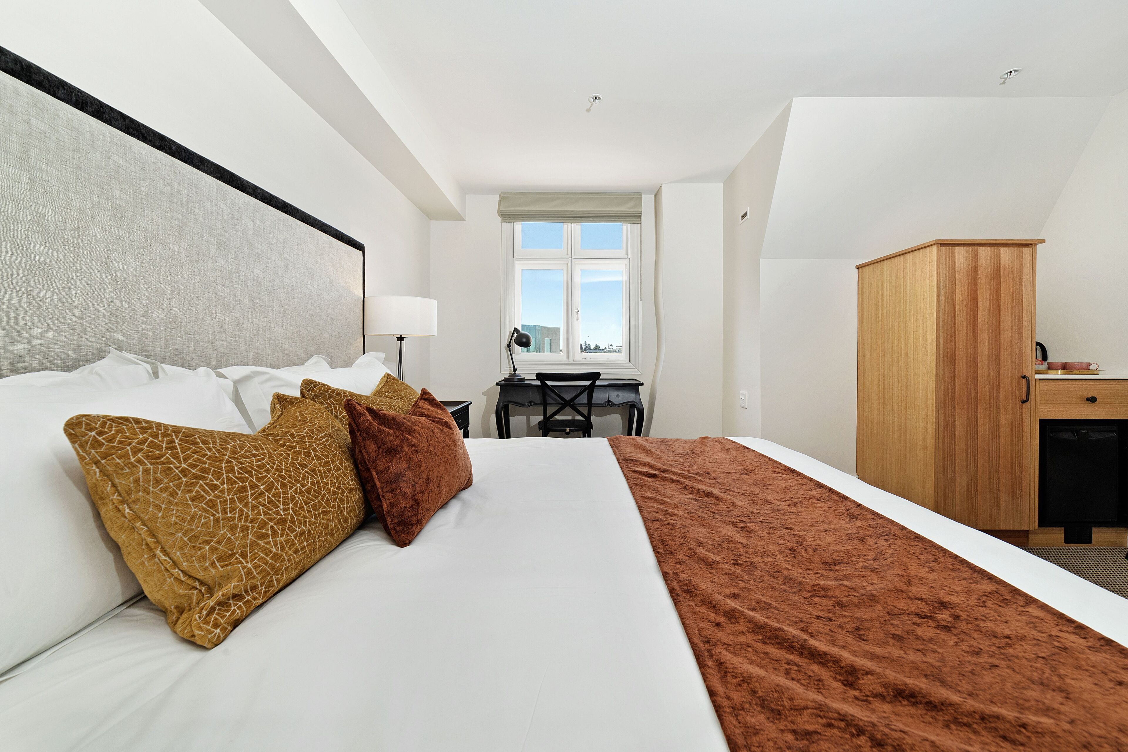 Ett hotellrum med en stor säng, ett skrivbord och en garderob.