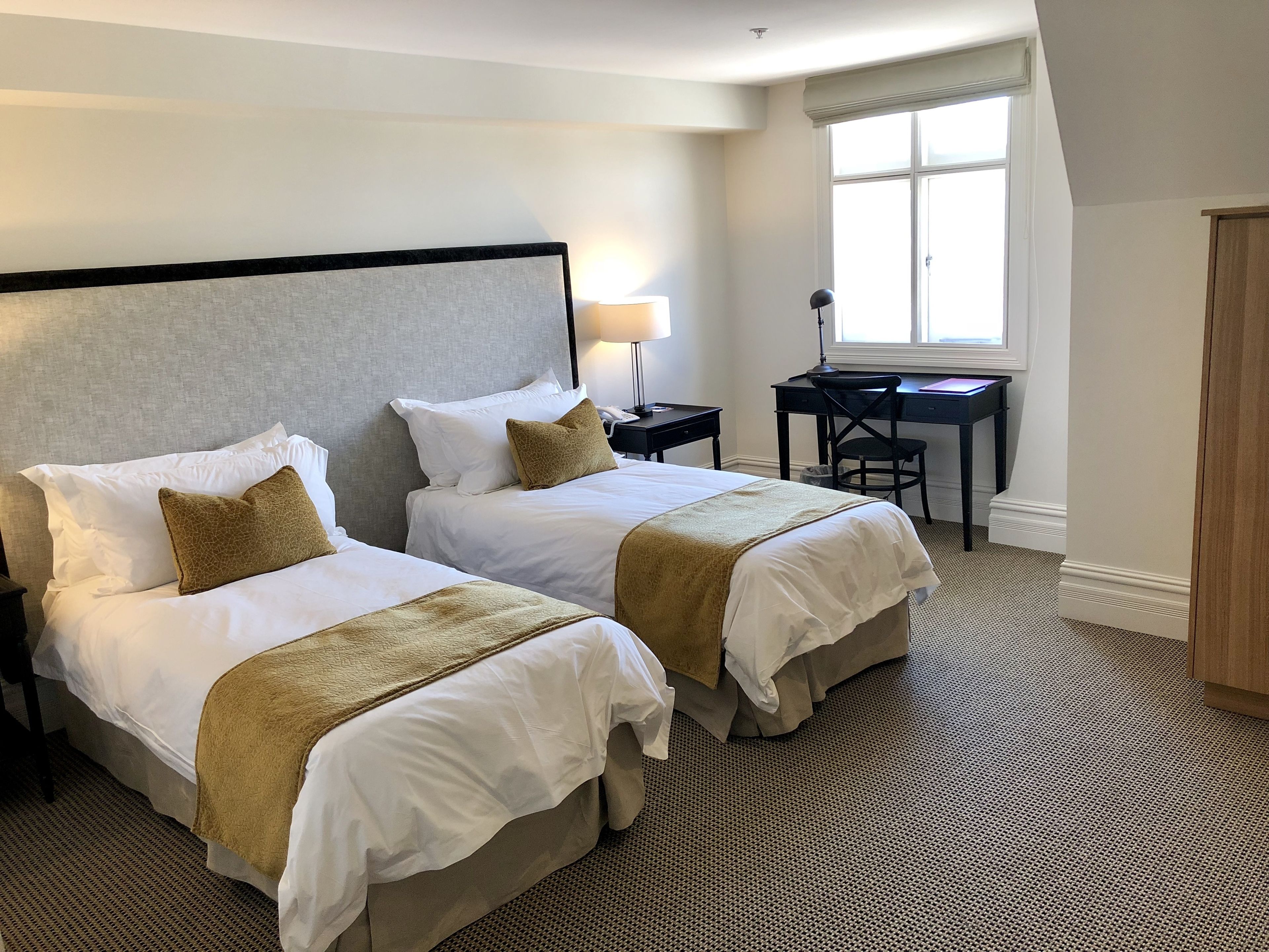 A hotel room with two beds, a desk, and a chair.