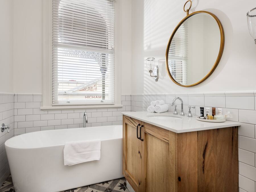 Ein modernes Badezimmer mit freistehender Badewanne, einem Holzbadezimmermöbel mit Waschbecken und einem großen Spiegel.