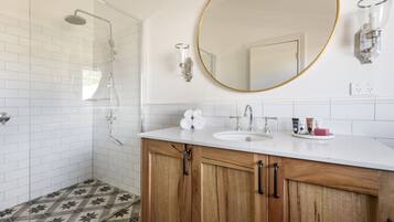 Un baño moderno con ducha, lavamanos y tocador con armarios de madera.