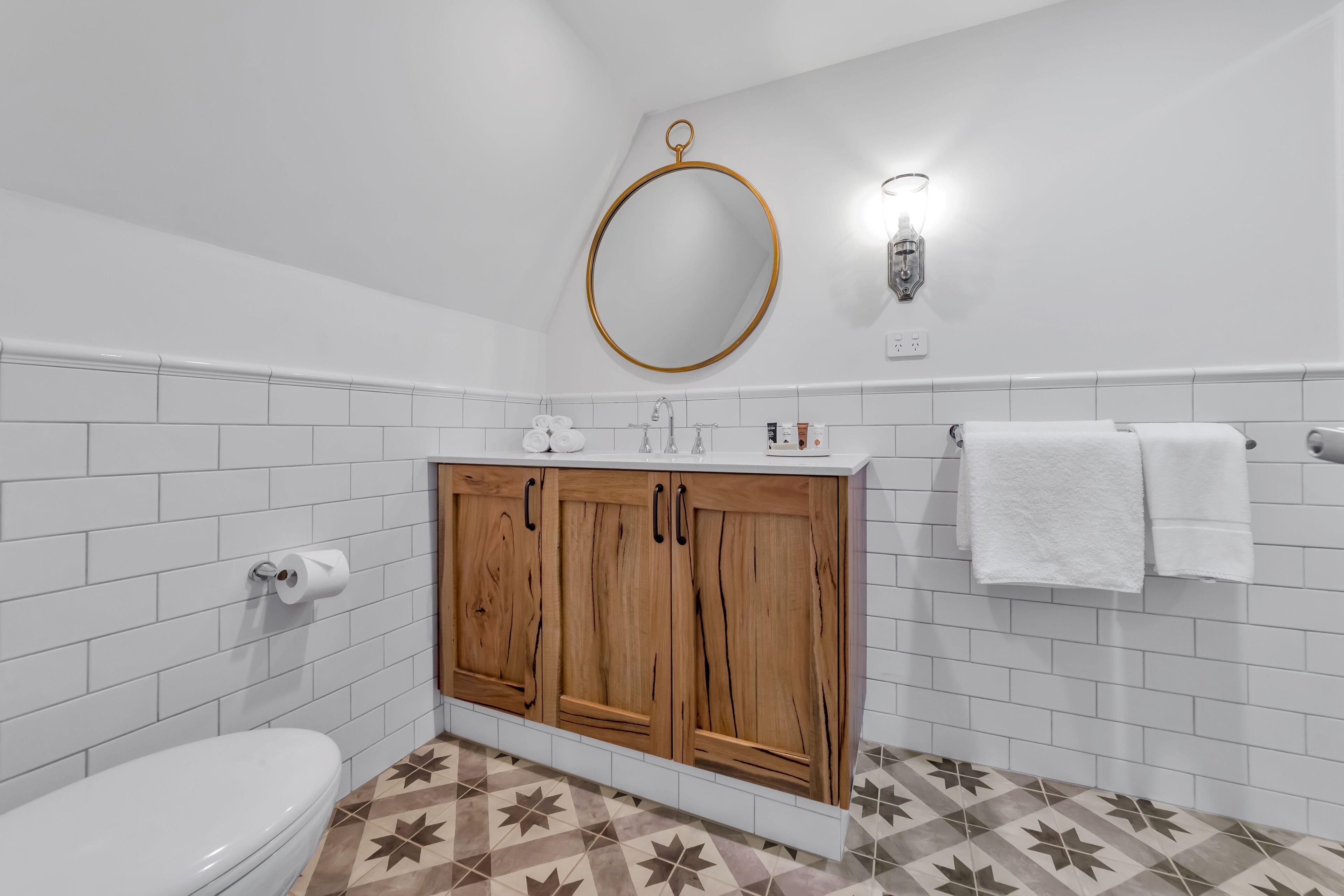 Ein Badezimmer mit Toilette, Waschbecken mit Spiegel darüber und Handtuchhalter.