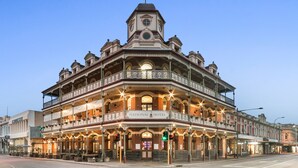 A historic hotel with a prominent clock tower, multiple balconies, and a well-lit facade. - The National Hotel (Fremantle)