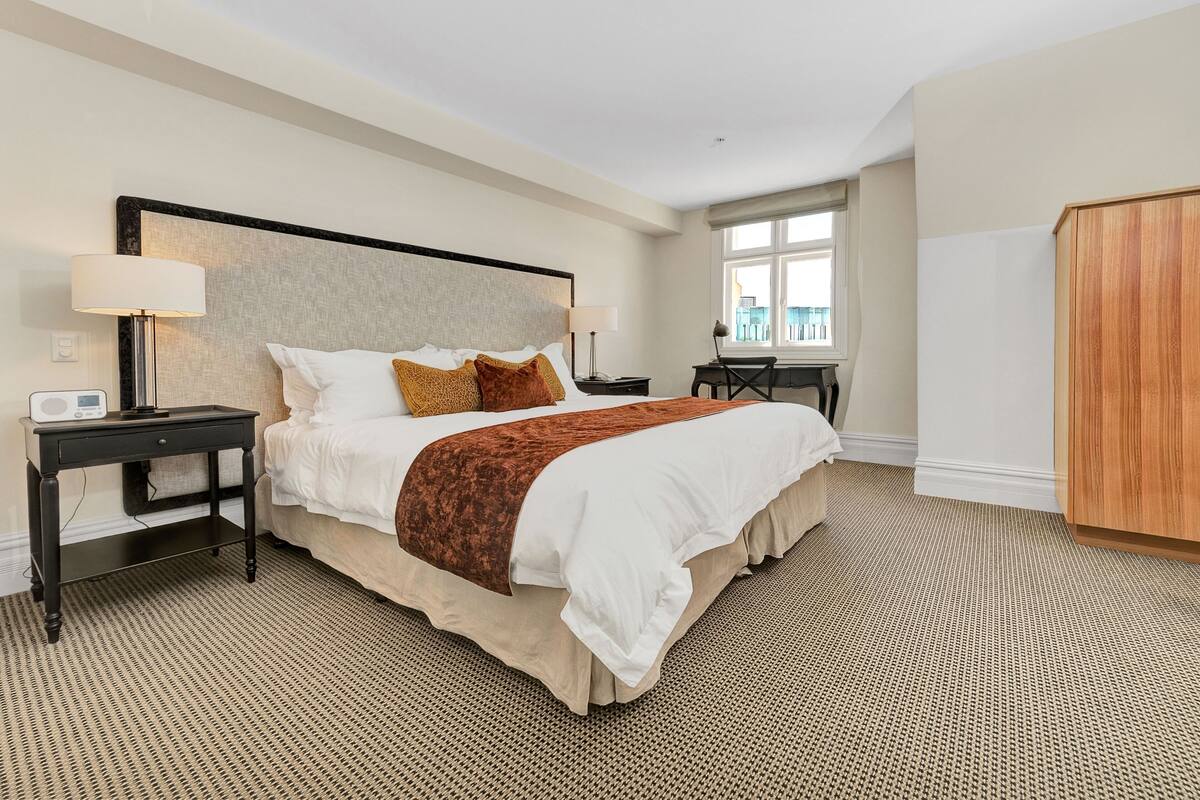 Une chambre d’hôtel avec un grand lit, un bureau, une chaise et une armoire.