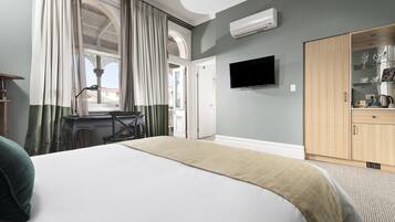 A hotel room with a bed, a desk, a television, and a wardrobe.