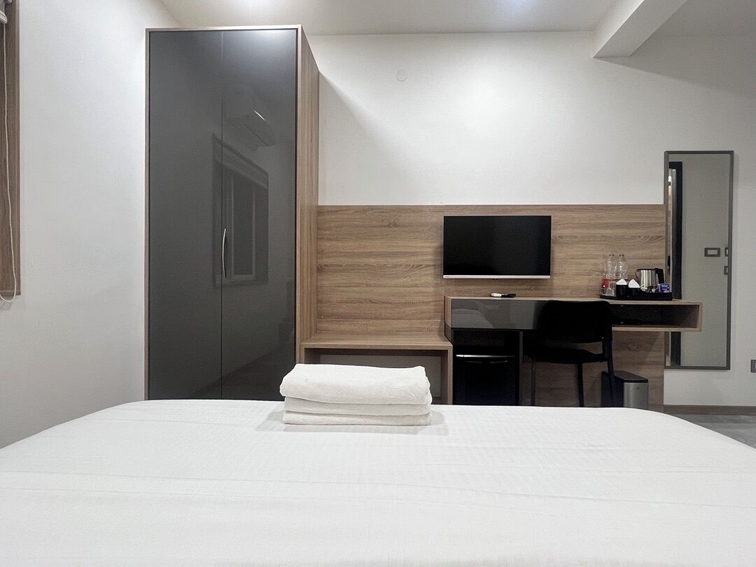 Une chambre d’hôtel comprenant un lit, un bureau avec une chaise, une télévision et une armoire.