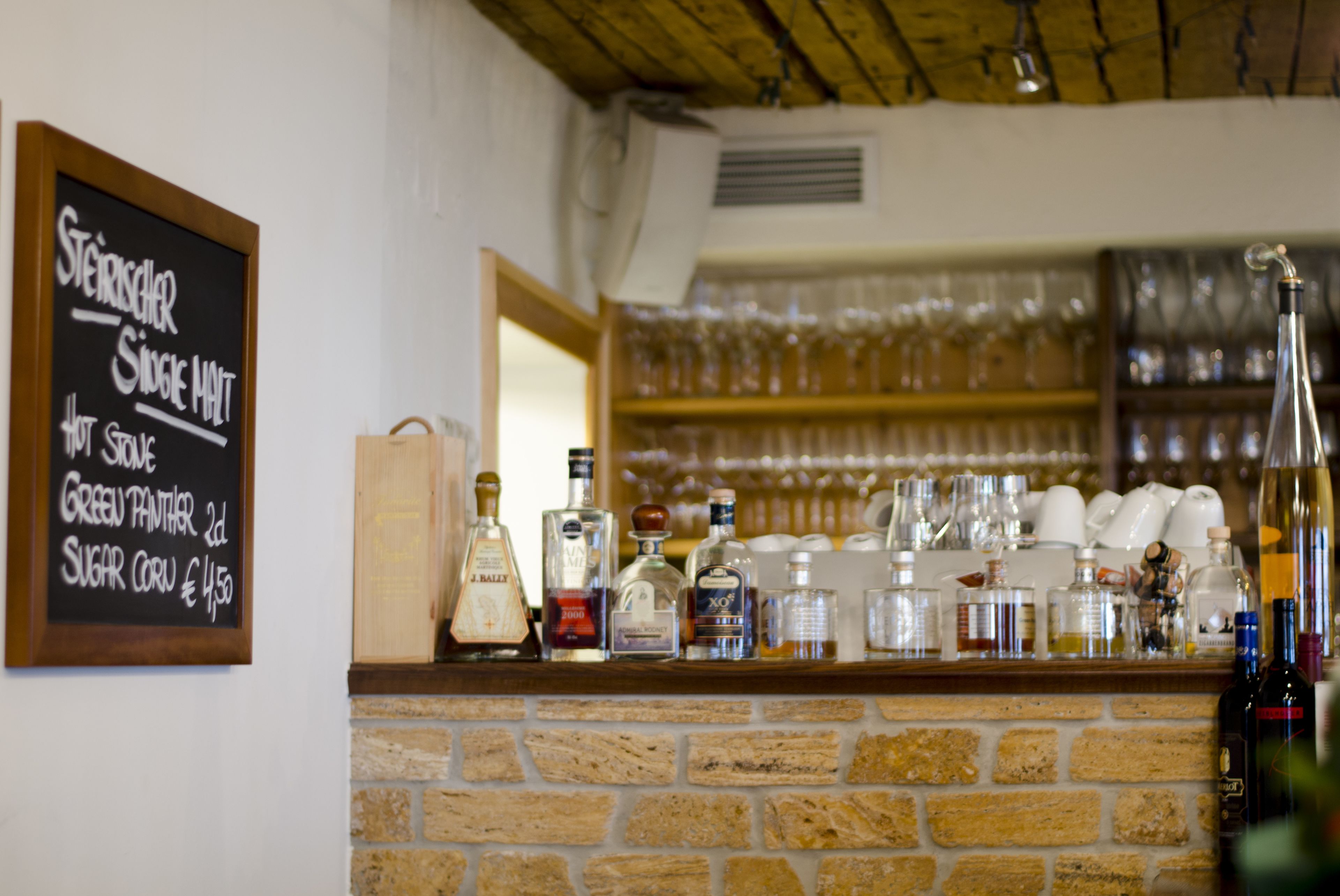 A bar area with a chalkboard menu listing items like 'Steinscher Single malt' and 'Green Panther 2dl'.