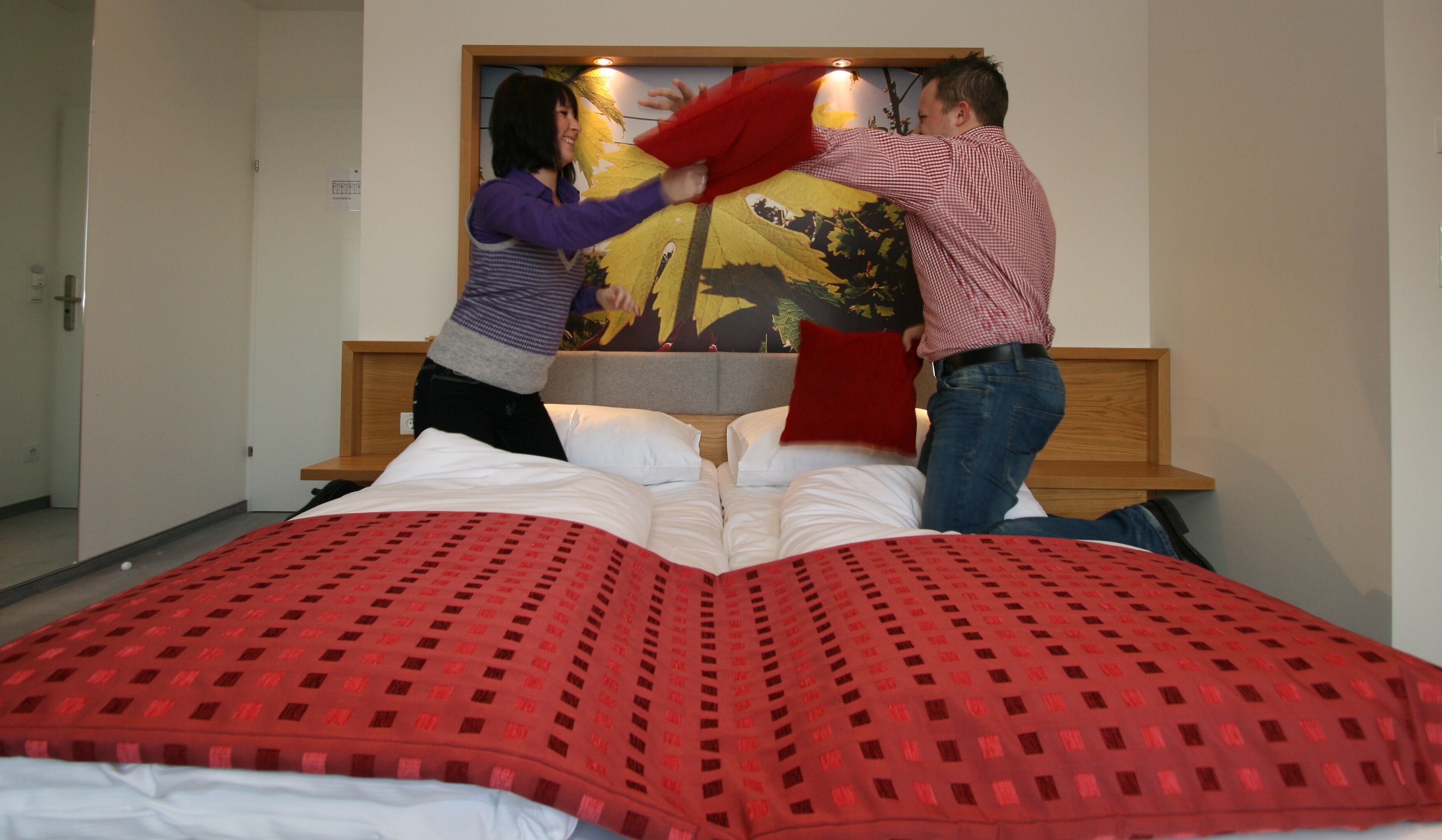 Una habitación de hotel con una cama grande, cabecera de madera y un cuadro colgado en la pared.