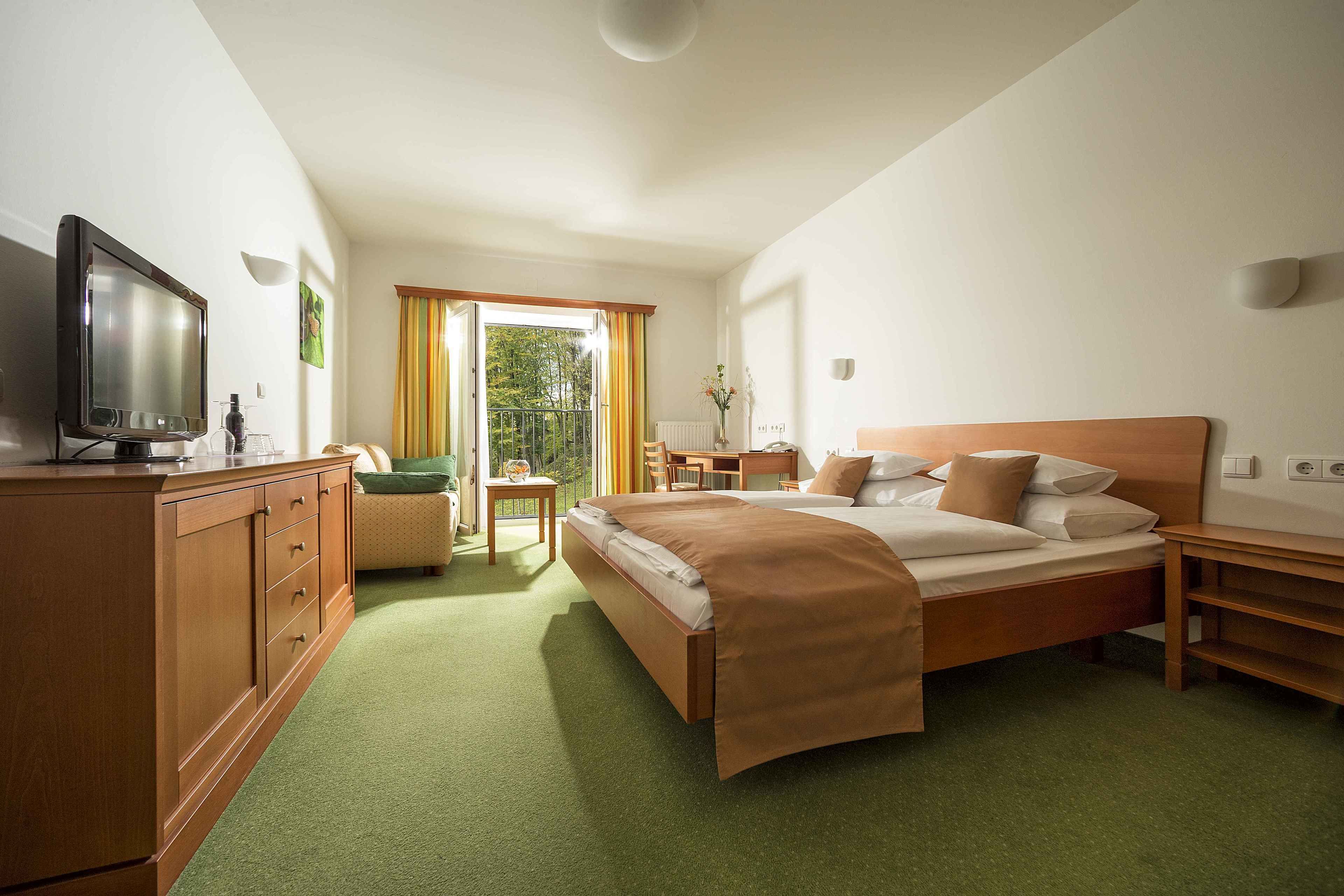 A hotel room with a bed, a TV, a desk, and a chair.