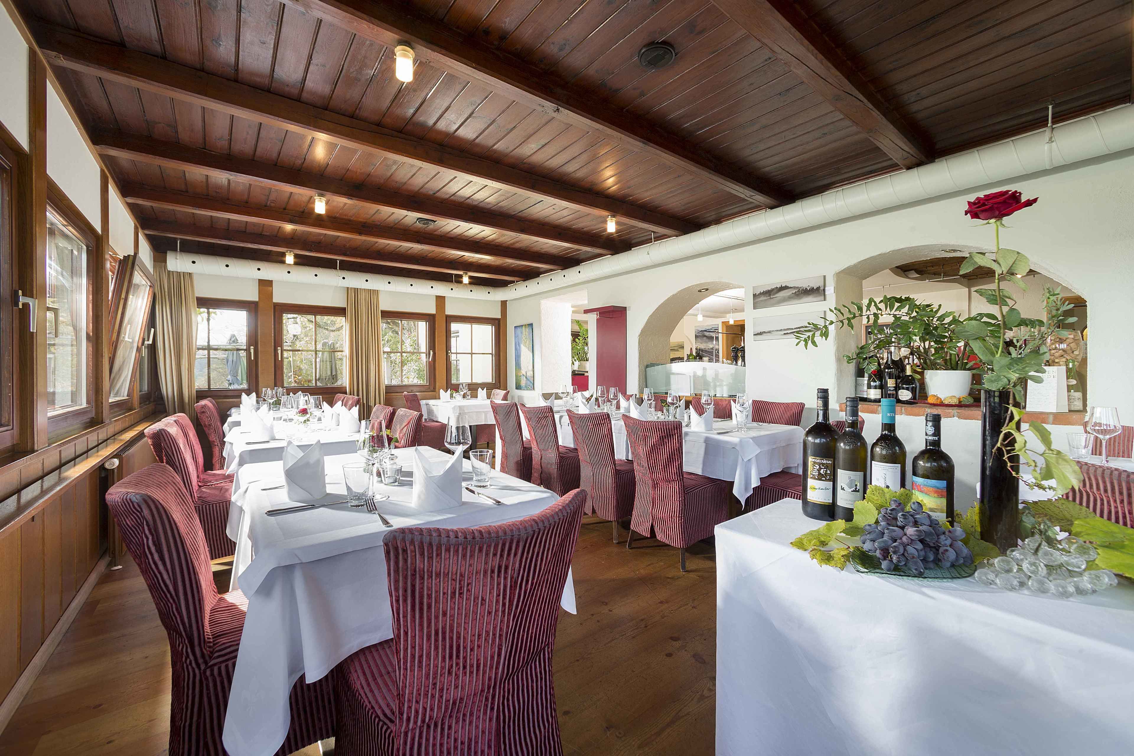 Un restaurante con techos de madera, sillas rojas a rayas y mesas dispuestas para comer.
