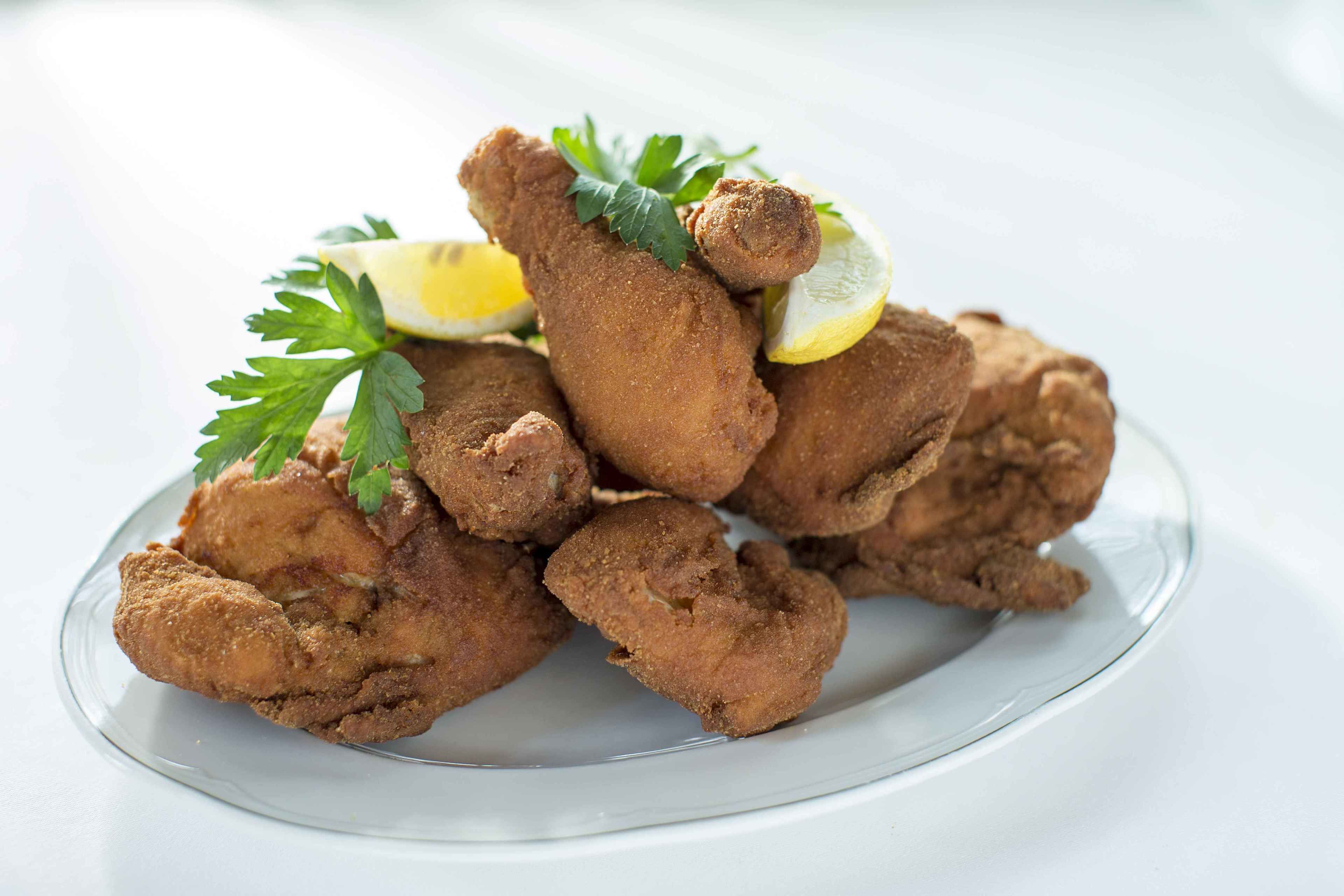 A plate of fried chicken garnished with parsley and lemon slices.