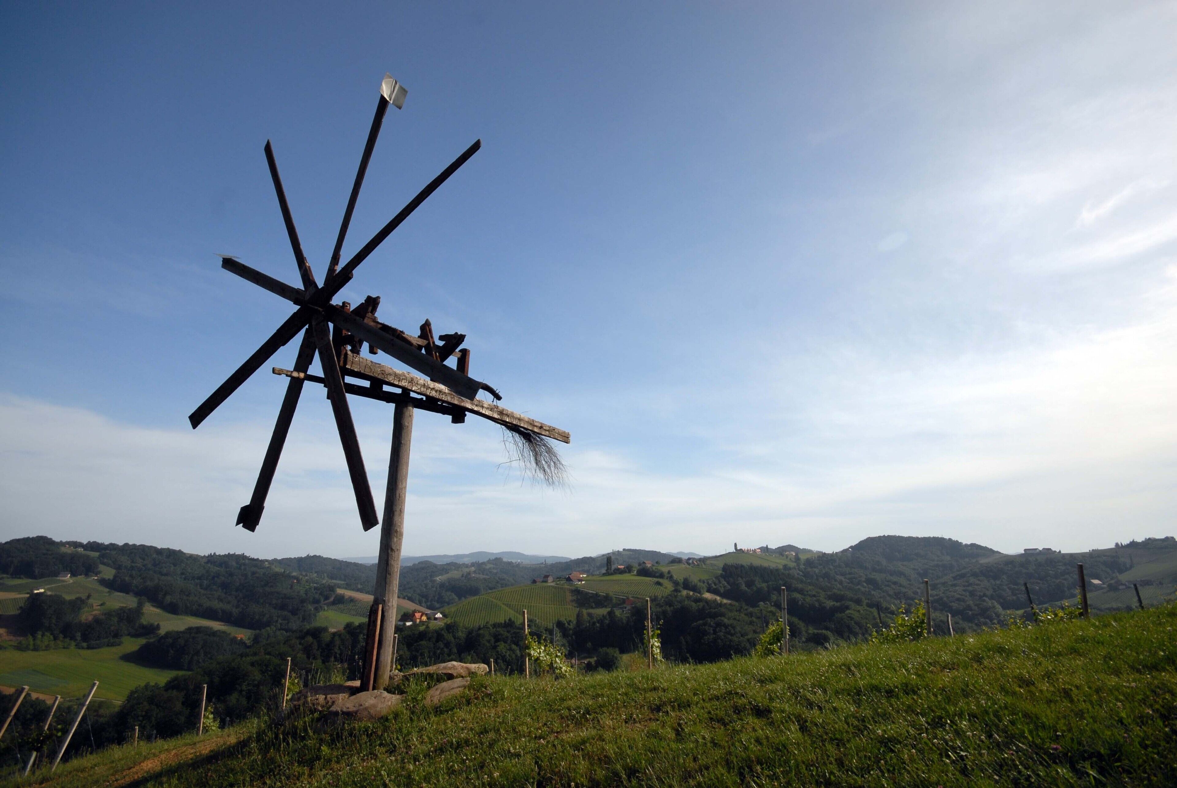 Un molino de viento en una colina con vistas a ondulantes colinas y un cielo despejado.