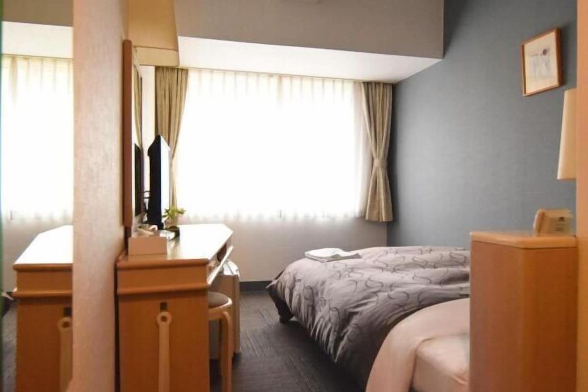 A hotel room with a bed, a desk, and a chair.