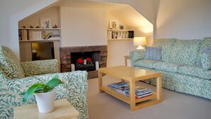 A cozy living room with a fireplace, patterned furniture, and bookshelves. - Sophisticated Edinburgh Apartment in City Centre (Edinburgh)