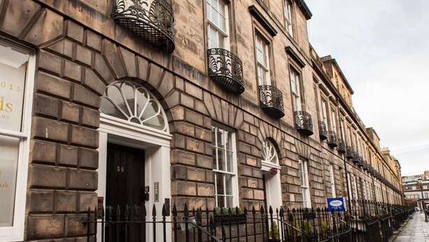 A row of traditional stone buildings with black iron balconies and a clear blue sky. - Sophisticated Edinburgh Apartment in City Centre (Edinburgh)