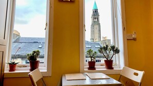 A room with two windows, each with a potted plant on the sill. A clock is visible on the wall. - Sophisticated Edinburgh Apartment in City Centre (Edinburgh)