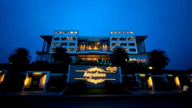Un hotel con un letrero llamativo que dice "Anjushree" en letras iluminadas, varios pisos y un diseño arquitectónico moderno.