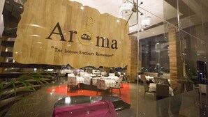 Un restaurante llamado "Aroma" con un cartel que indica que es restaurante de especialidad india.