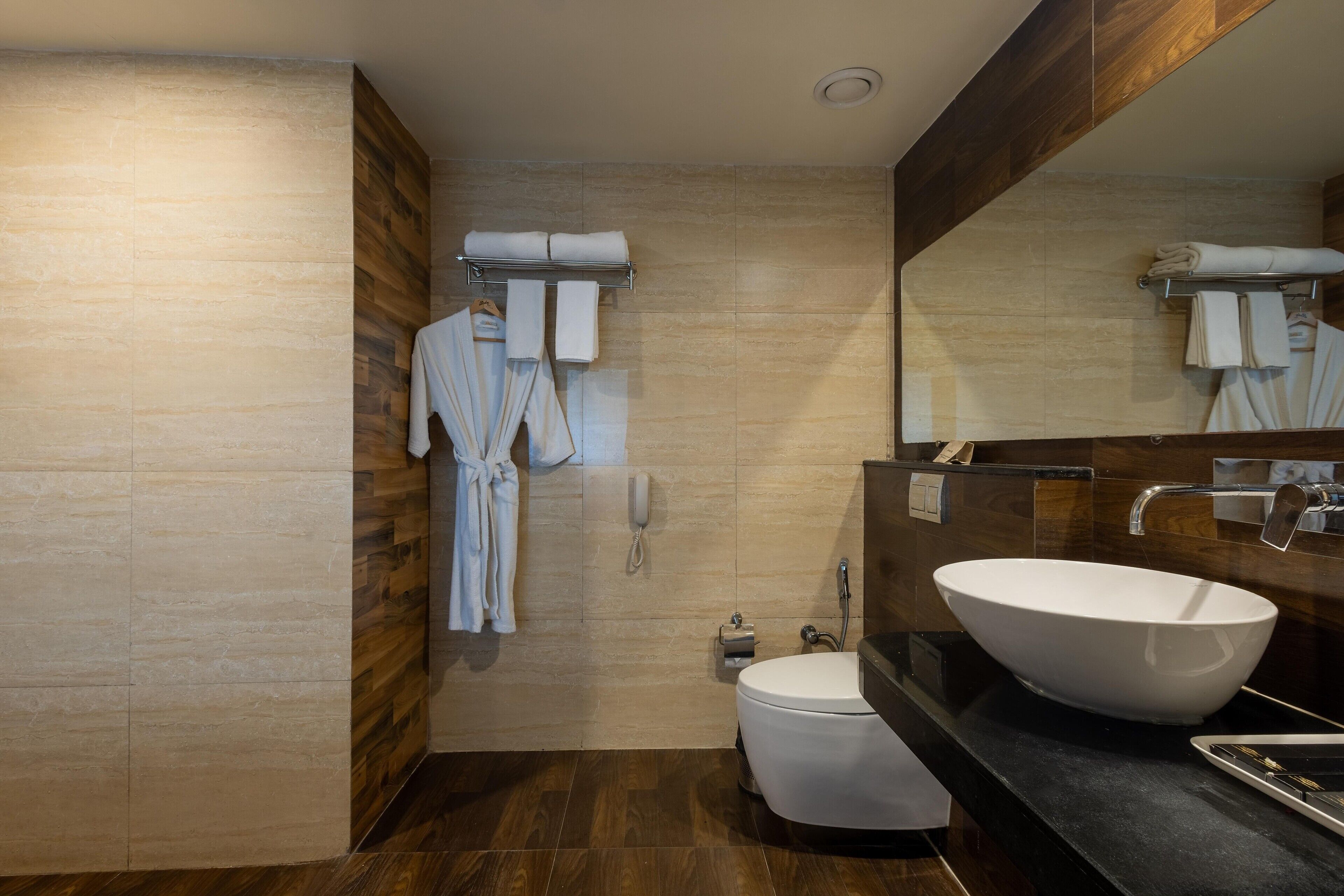 Een moderne badkamer met een grote spiegel, een wit wastafelmeubel en een toilet.