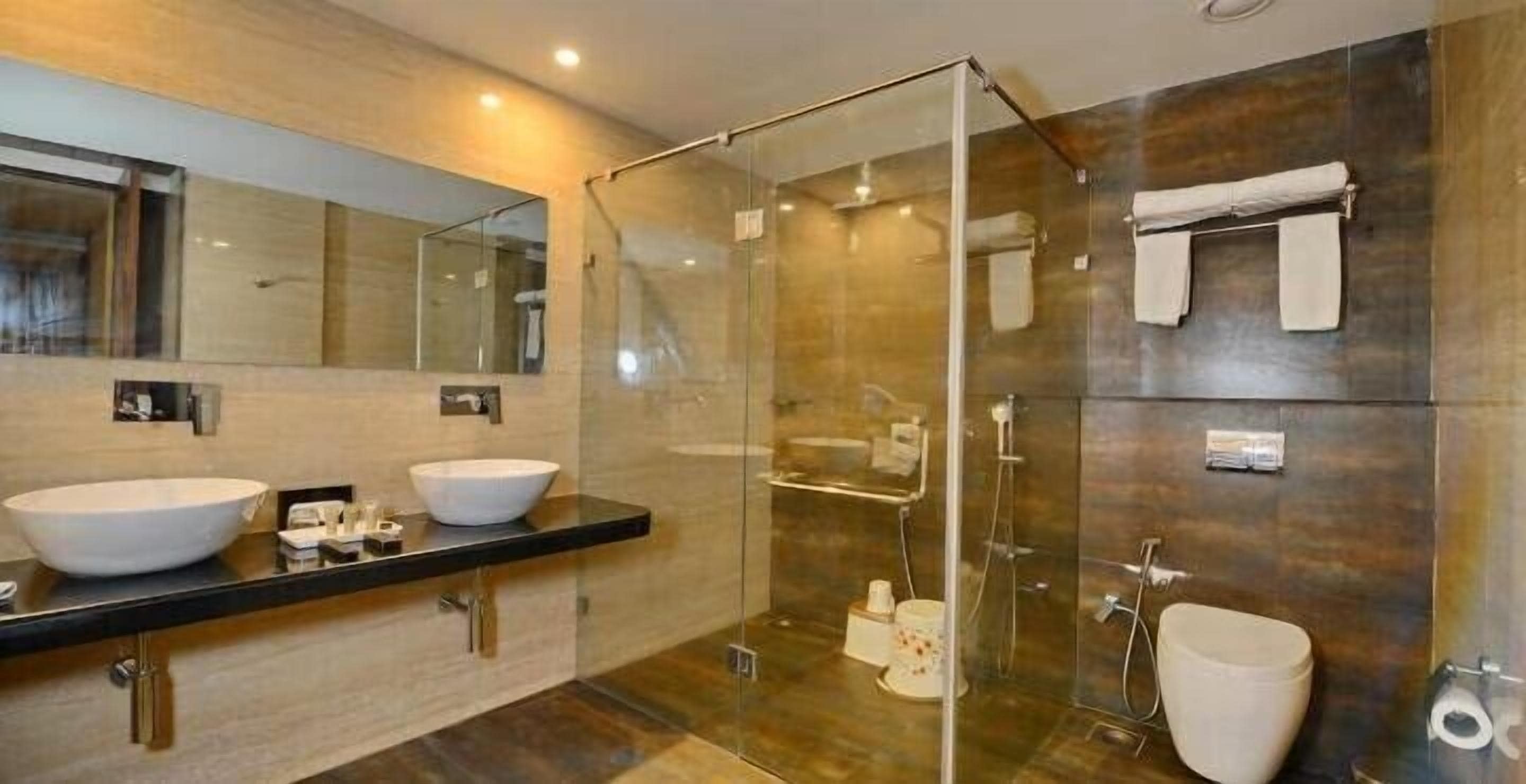 Un baño moderno con dos lavamanos, cabina de ducha de vidrio y un inodoro.