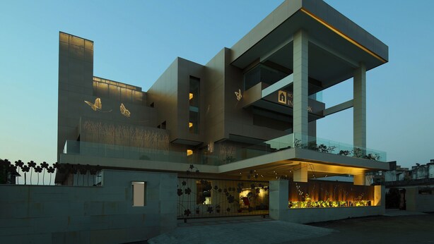 A modern multi-story building with balconies, large windows, and a well-lit entrance.