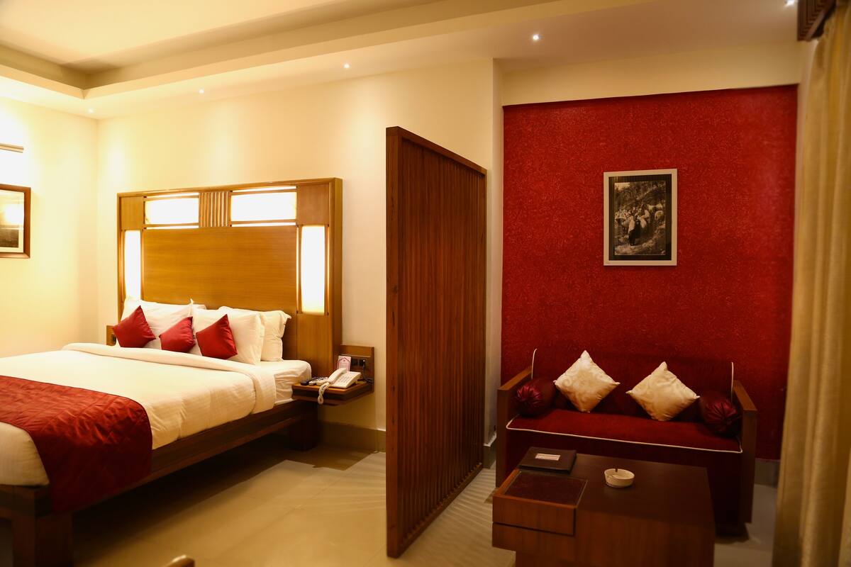 Una habitación de hotel con cama, mesita de noche y sofá.