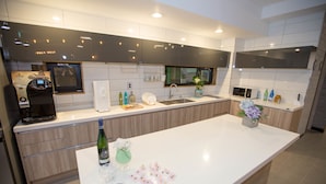A modern kitchen with a large island, built-in appliances, and a window. - Hotel Ggulzam (Yeosu)