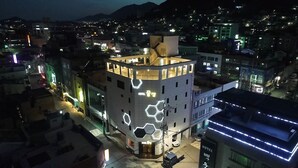 A hotel with a unique hexagonal light design on its facade, located in an urban area with surrounding buildings. - Hotel Ggulzam (Yeosu)