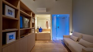 A modern living room with a wooden floor, a beige sofa, and a built-in shelving unit with framed pictures. - Massimago Wine Suites (Verona)