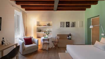 Une pièce moderne et bien éclairée, avec un plafond en bois, un canapé blanc, une table à manger avec des chaises, une petite table blanche ornée d’un vase et un lit.