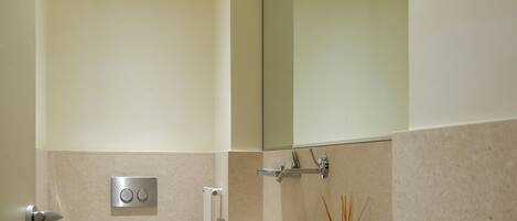 A modern bathroom with a toilet, sink, mirror, and towel rack.