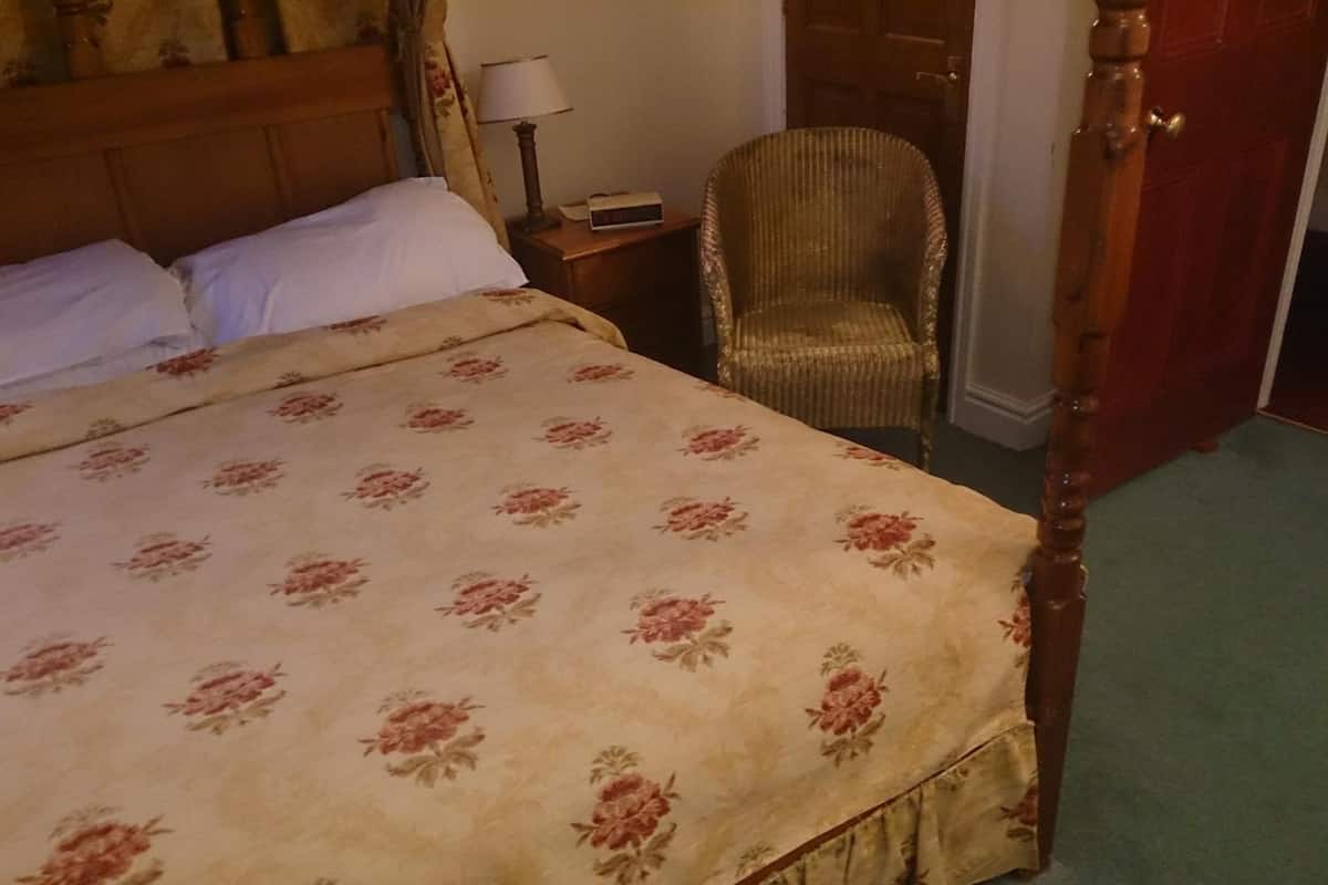 A bedroom with a large bed, a chair, a nightstand, and a door.