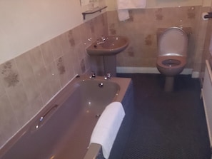 A bathroom with a bathtub, a sink, and a toilet. - OYO Rose & Crown Hotel (Leyburn)