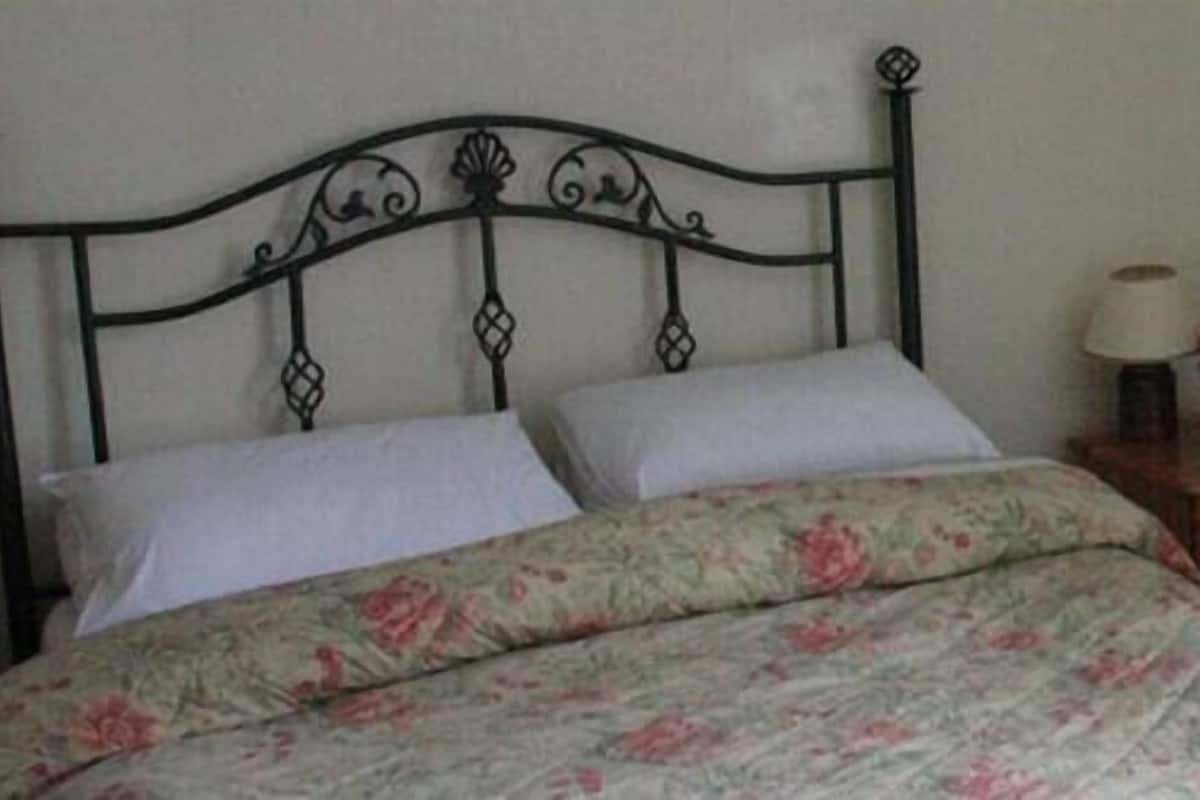A bed with a floral bedspread and a metal headboard.