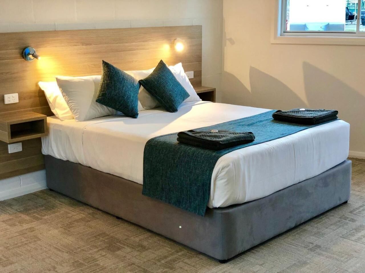A modern bedroom with a large bed, two bedside tables, and a window with a view.