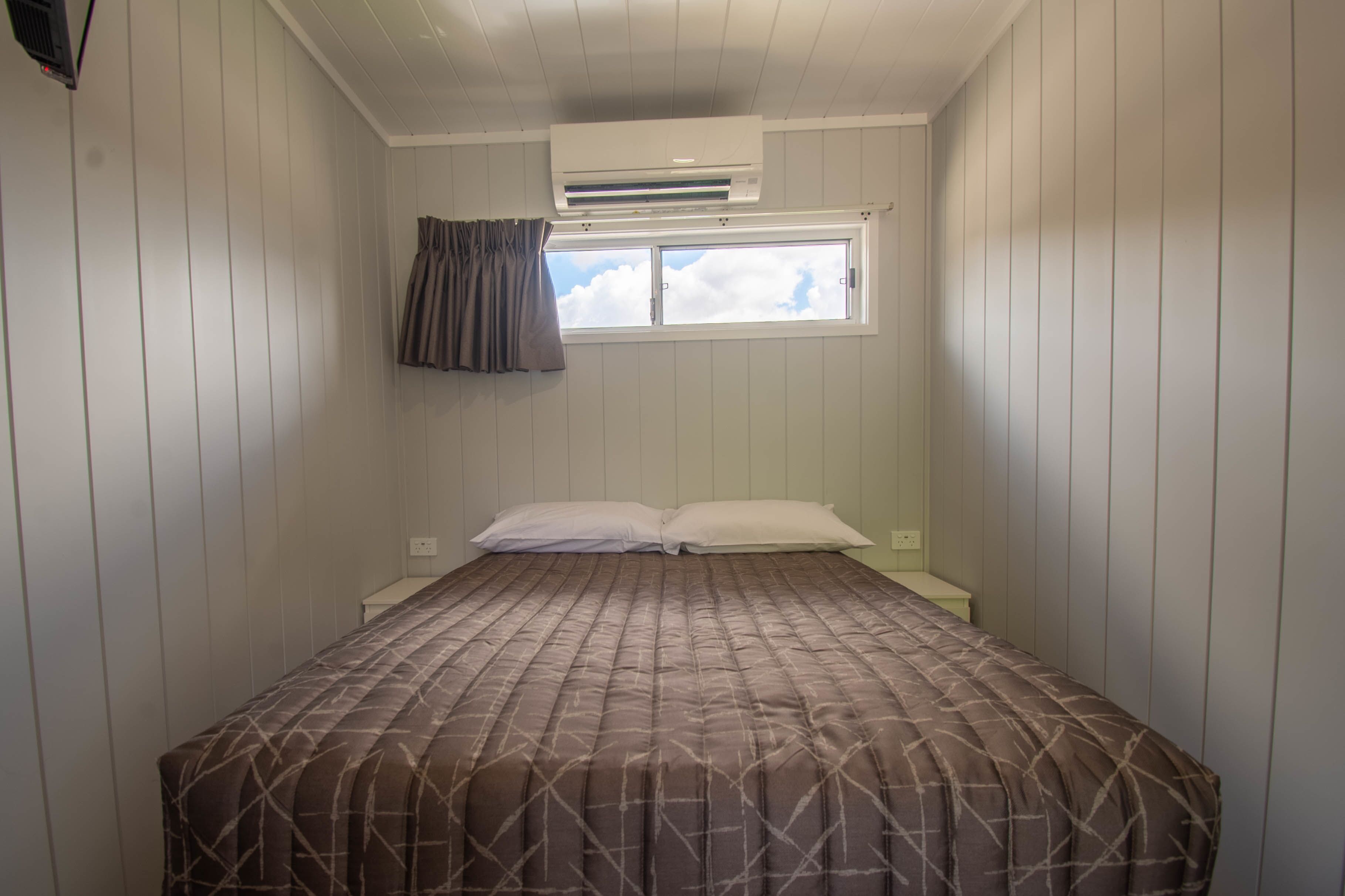 Un dormitorio con cama, ventana y aire acondicionado.
