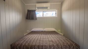 Un dormitorio con cama, ventana y aire acondicionado.