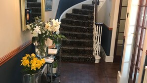 A hallway with a wooden floor, a decorative rug, a staircase with a dark wall, and a door on the right. - Broom Lodge (Largs)