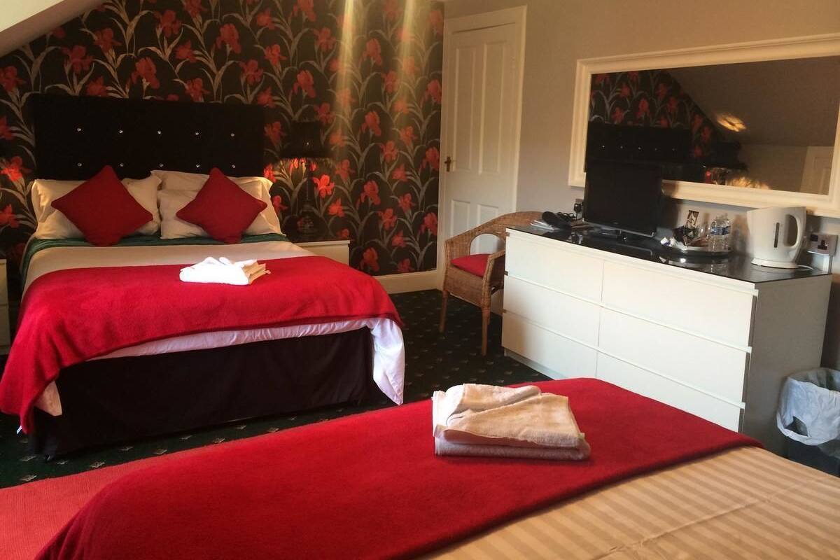 Quarto com duas camas, cômoda, cadeira e cozinha compacta.