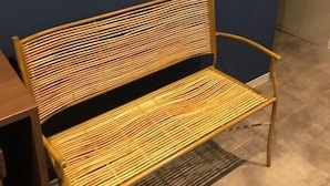 A wooden bench with a slatted backrest and seat, positioned against a dark wall with a logo above it. - POPTONE the Guest House - Hostel (Hiroshima)