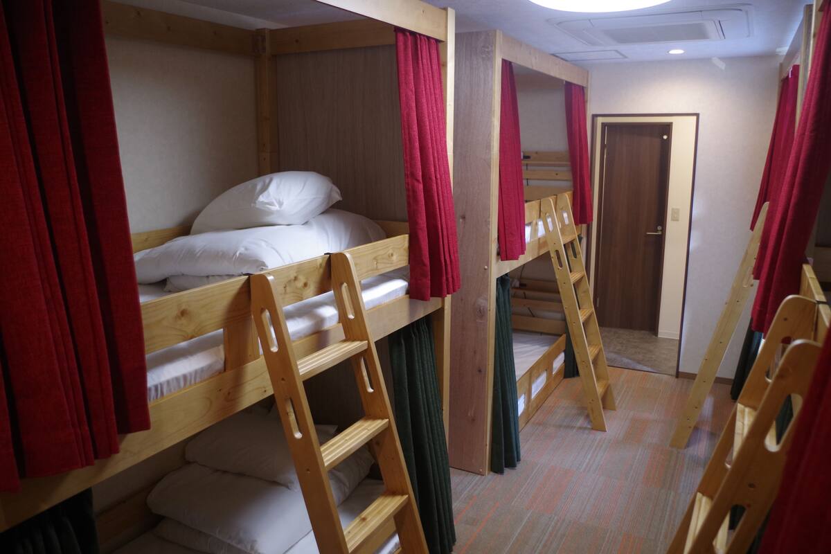 Un dormitorio con literas, muebles de madera y cortinas rojas.