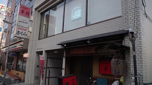 A building with a sign for a restaurant, a bicycle parked outside, and a neon sign above the entrance. - POPTONE the Guest House - Hostel (Hiroshima)