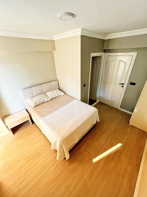 Ein Schlafzimmer mit Bett, Nachttisch, Tür und Kleiderschrank.