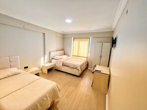 Ein Schlafzimmer mit Doppelbett, Nachttisch, Kleiderschrank und einem Fenster mit Vorhängen.